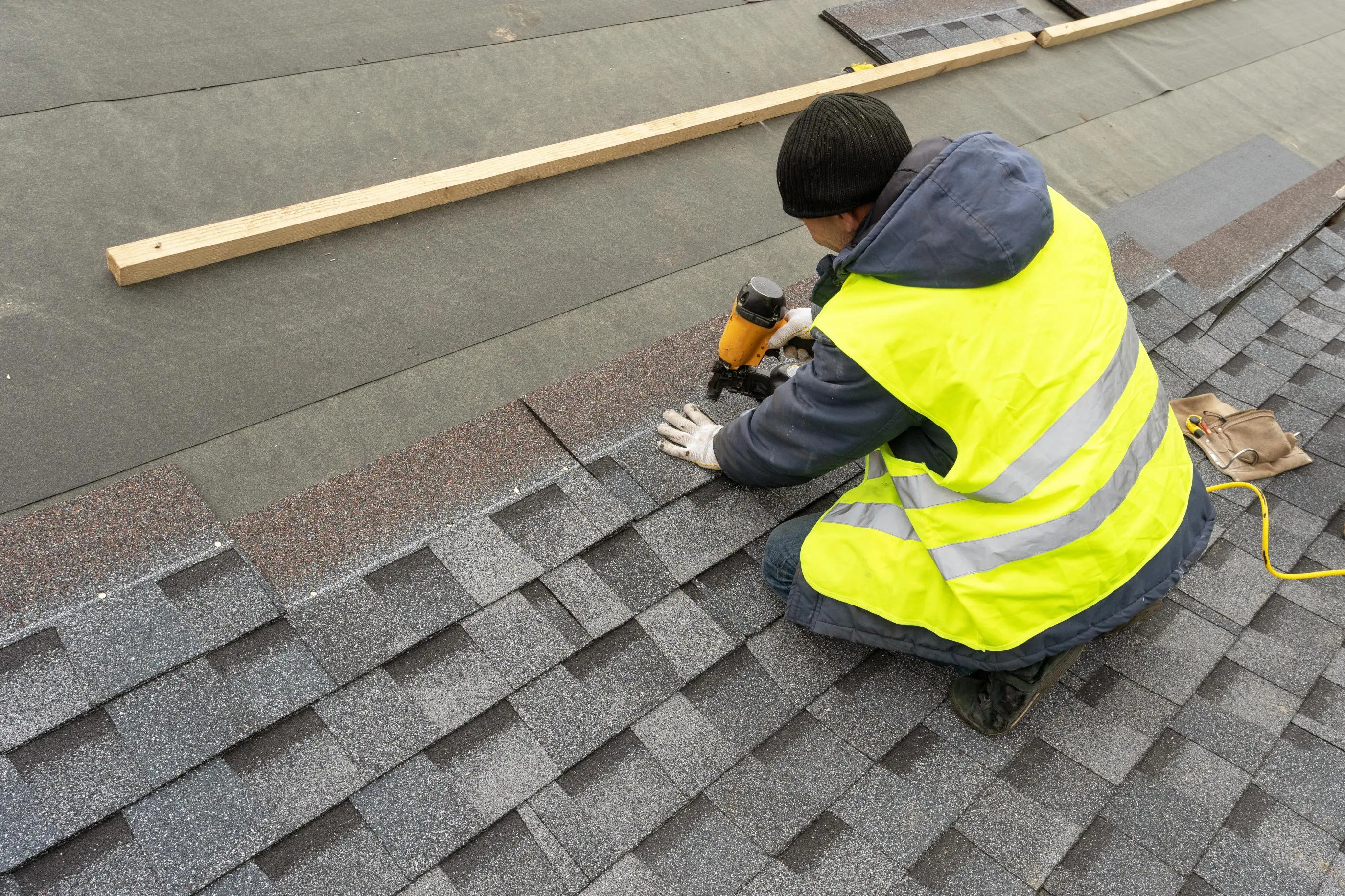 Worker installing shingles on a roof.
