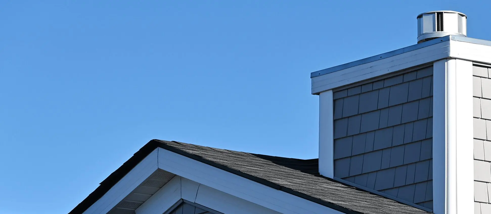 House roof and chimney against blue sky.