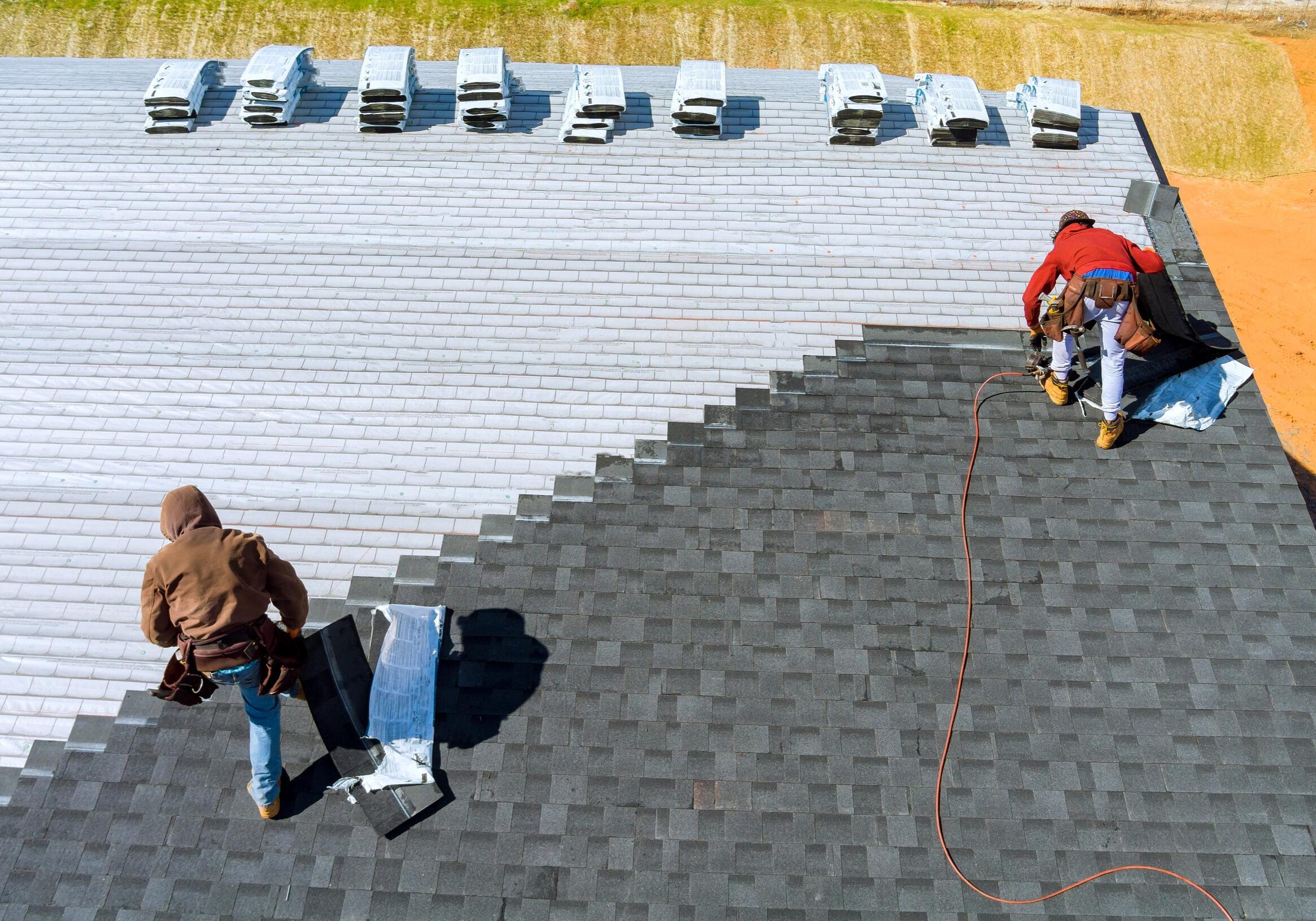 Roofers installing shingles on a roof.